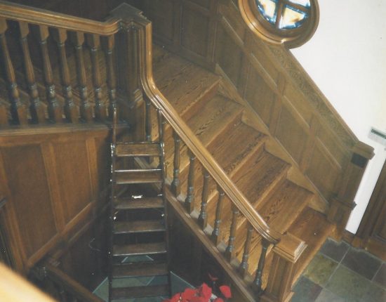 Red oak staircase with wood wainscoting and balustrade.