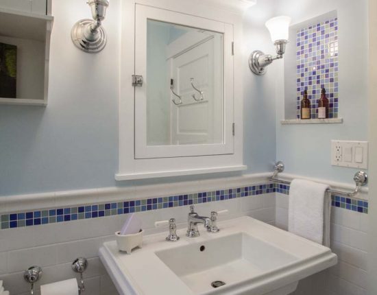 A kid's bath with pedestal sink and decorative mosaic tile