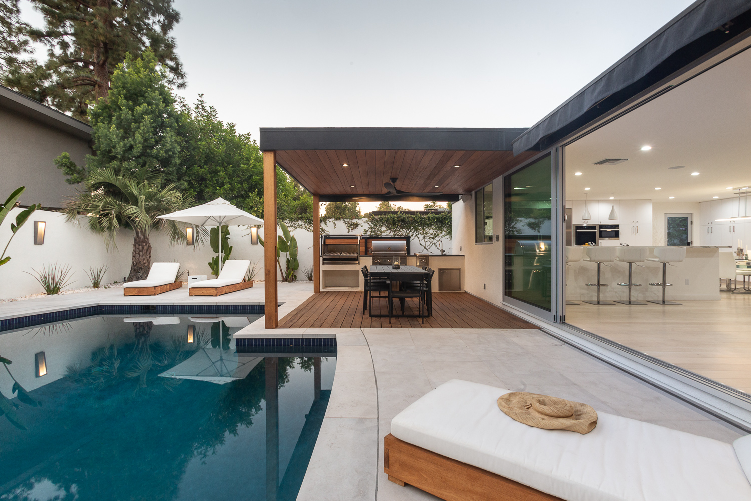 Outdoor living space with lounge seating, dining table, and full outdoor kitchen and BBQ