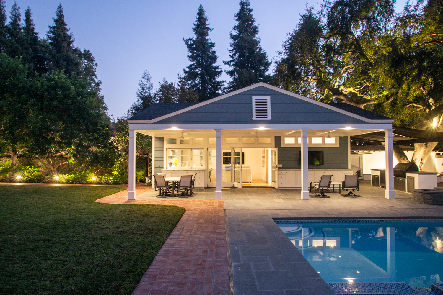 Pool house with outdoor living space including seating, TV and Outdoor Kitchen.