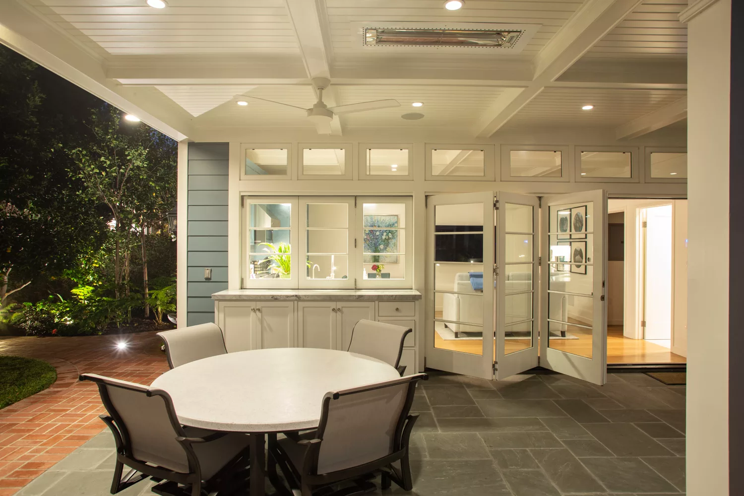 Pool house with outdoor living space including seating and window to kitchen.