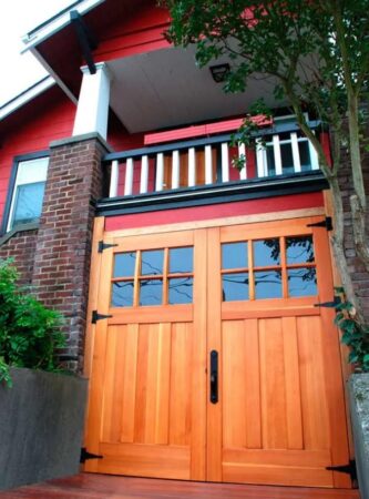 Garage space is tucked between brick piers underneath a porch. The open-swing new doors work in this case, and their Craftsman design pulls the facade together. 