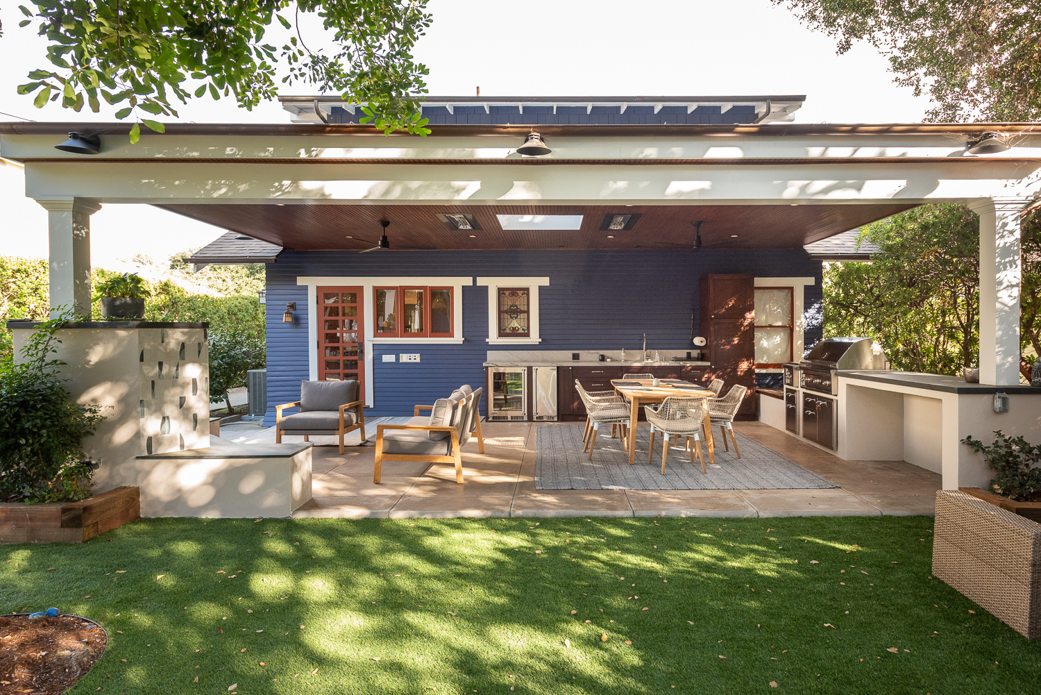 Outdoor living space with dining area, fireplace, and outdoor kitchen.