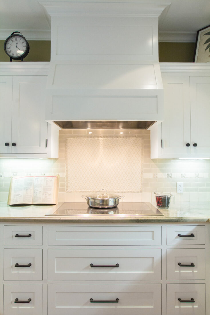Kitchen design with white cabinetry, ventilation hood, and electric stove